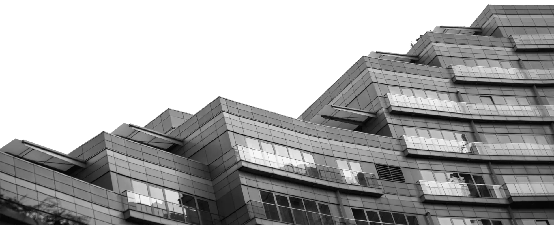 Mahbod Group Black and white photo of a modern, multi-storey hospitality building with glass windows and staggered, angular architectural design against a black background.